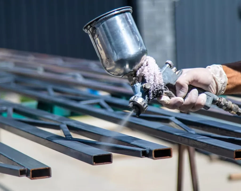 Electrostatic spray gun applying powder coating to steel railings