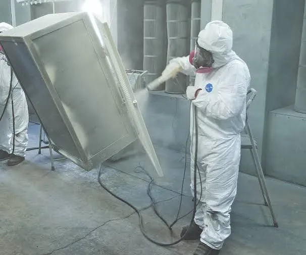 Technician sandblasting a metal cabinet in protective gear