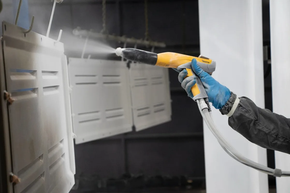 Technician applying powder coating with a professional electrostatic gun in our booth