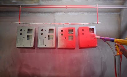 Red powder being electrostatically applied to metal panels